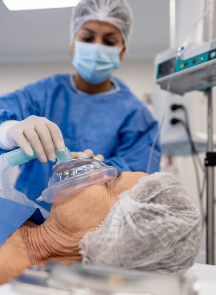 Doctor putting an oxygen mask on a patient under anesthesia at the hospital - operating room concepts